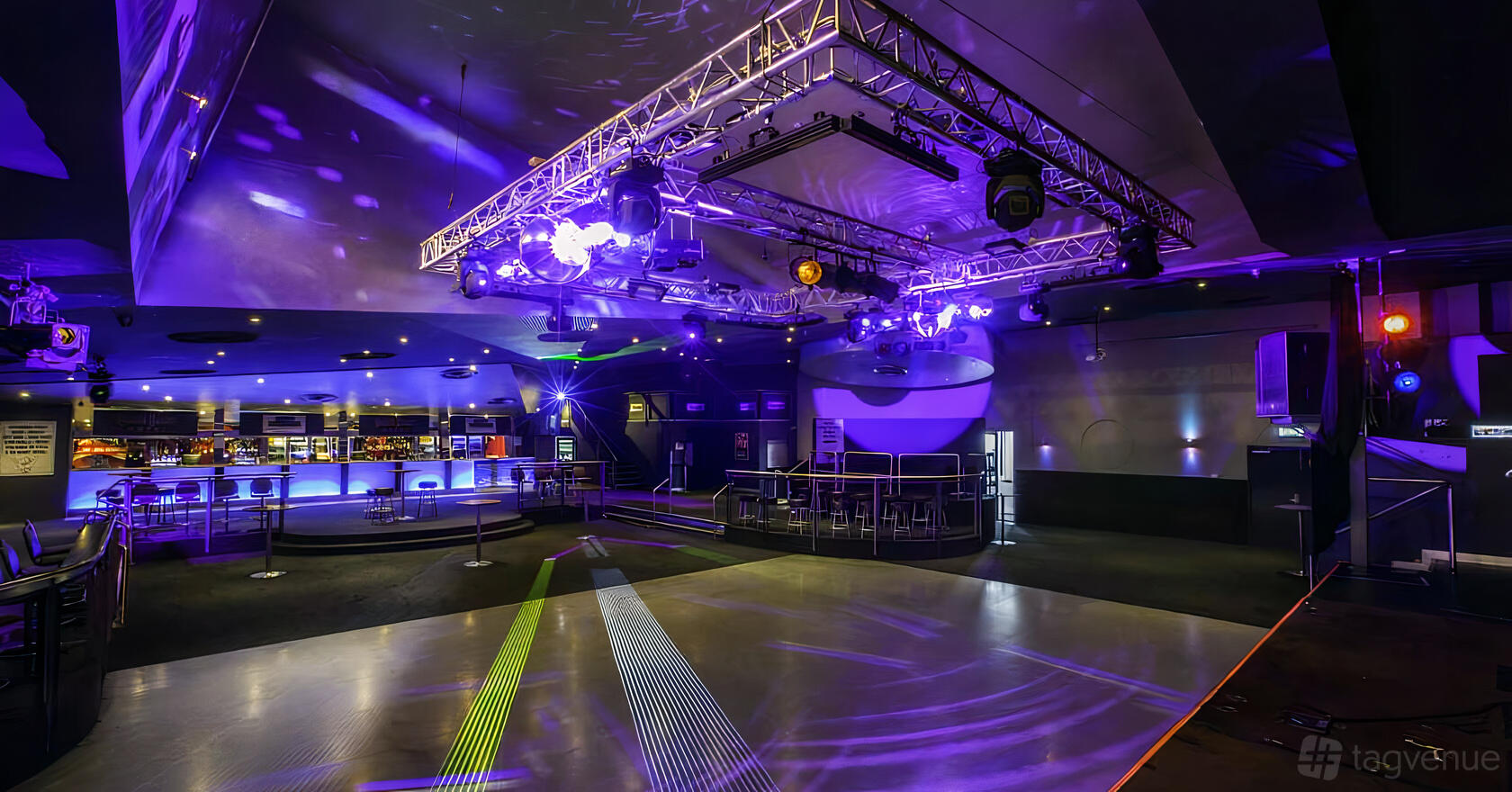 An event space with a large dance floor, stage, and colorful stage lighting at Chelsea Heights Hotel.