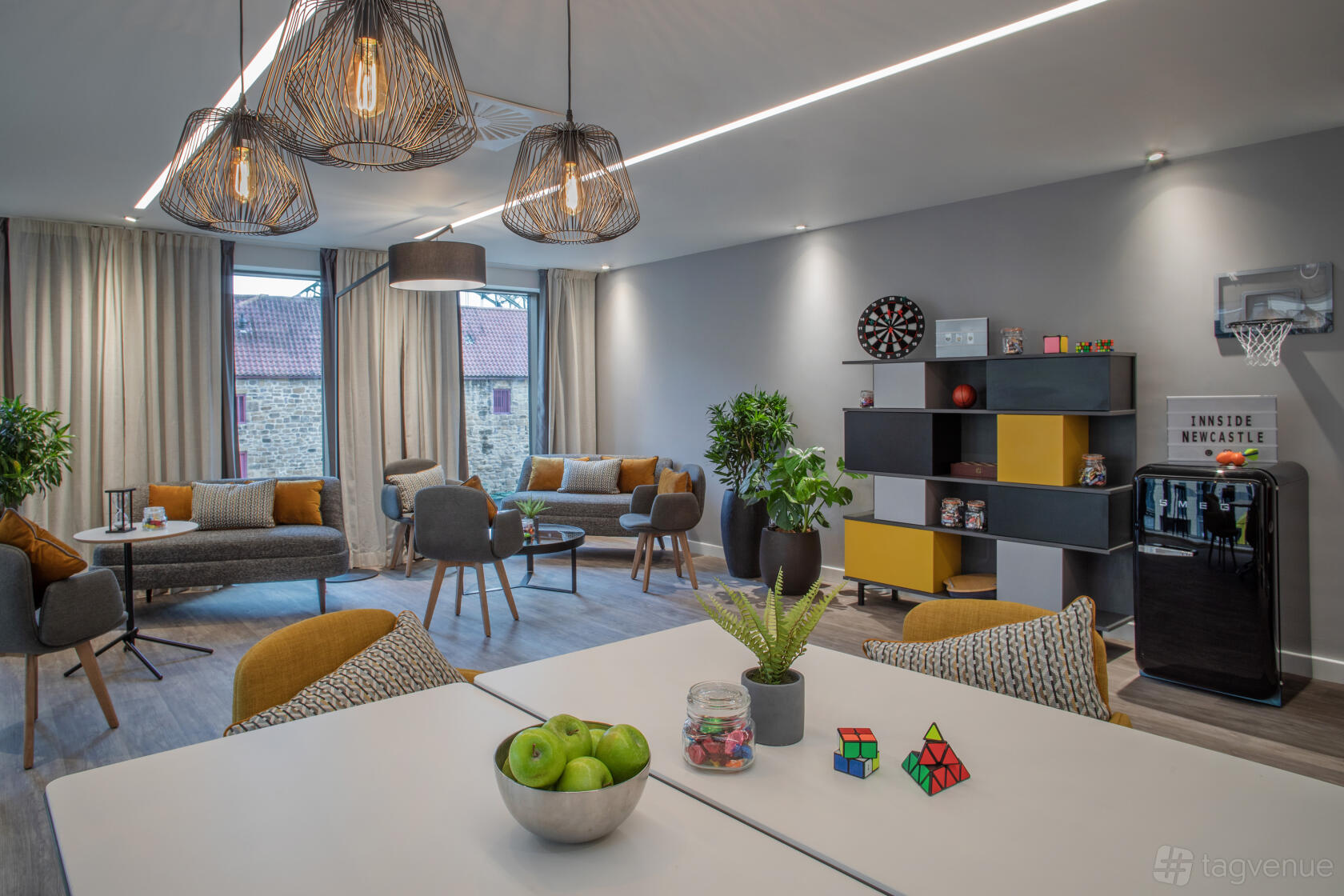 An event space in a hotel with lounge seating, large windows, pendant lights, and a games area at INNSiDE By Melia Newcastle.