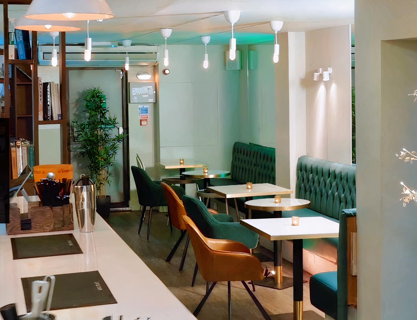 A bar lounge with tufted green banquette seating, marble tables, and teal chairs at Simul Place.