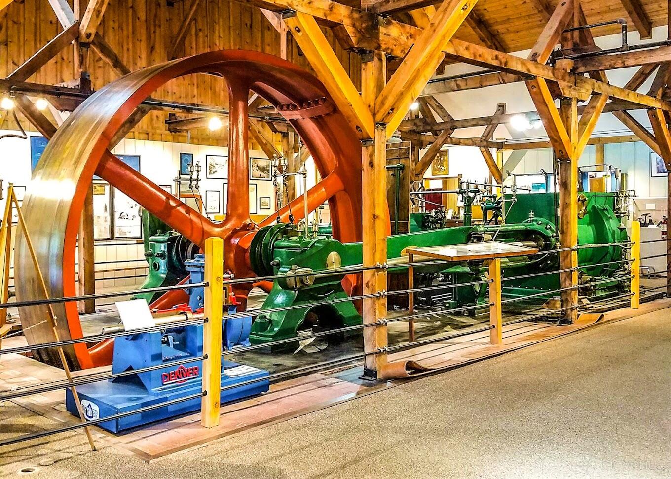 A museum gallery with exposed wooden beams and large industrial machinery at Western Museum of Mining and Industry.