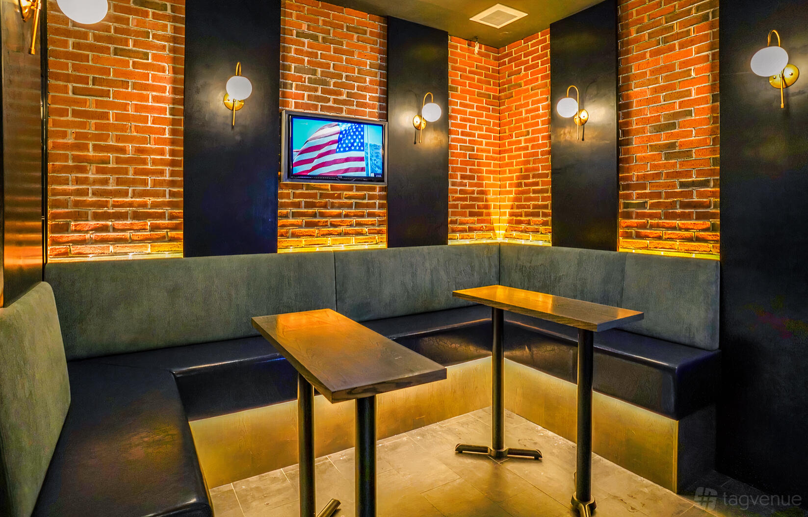 A karaoke bar with exposed brick walls, built-in bench seating, wall sconces, and a TV at MS. KIM'S Lounge & Private Karaoke.