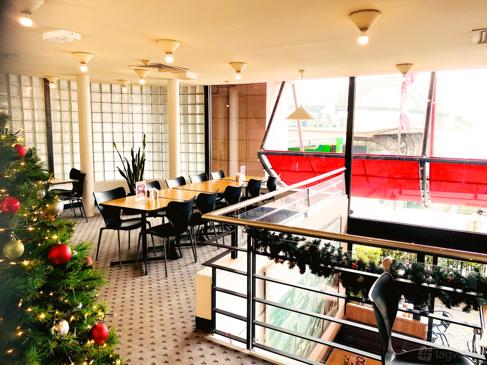 An event space in a restaurant with floor-to-ceiling glass windows, a decorated Christmas tree, and harbour views at City Extra.