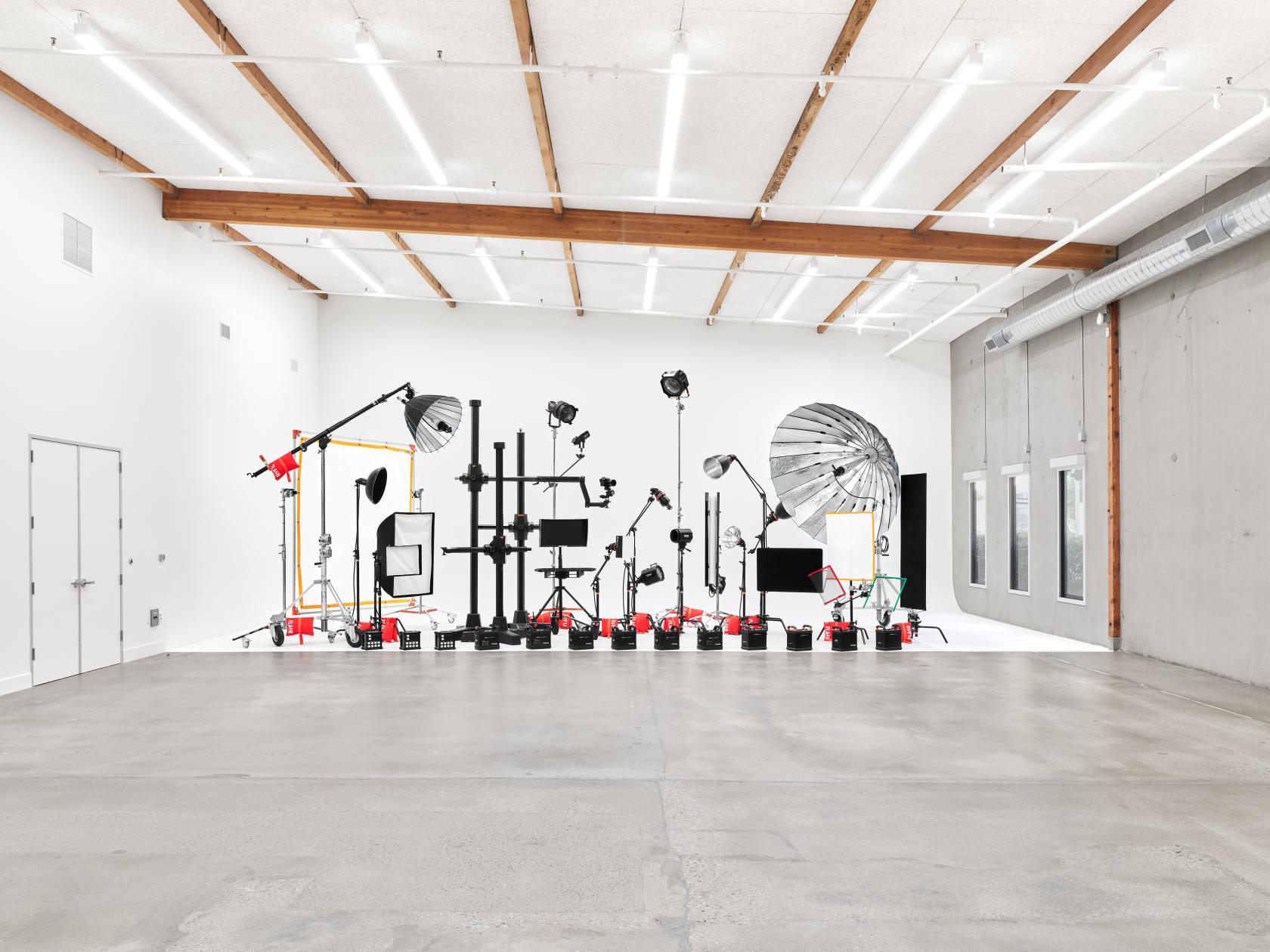A photo studio with professional lighting equipment, seamless white cyclorama, and exposed ceiling beams at Flash Photo Studio.