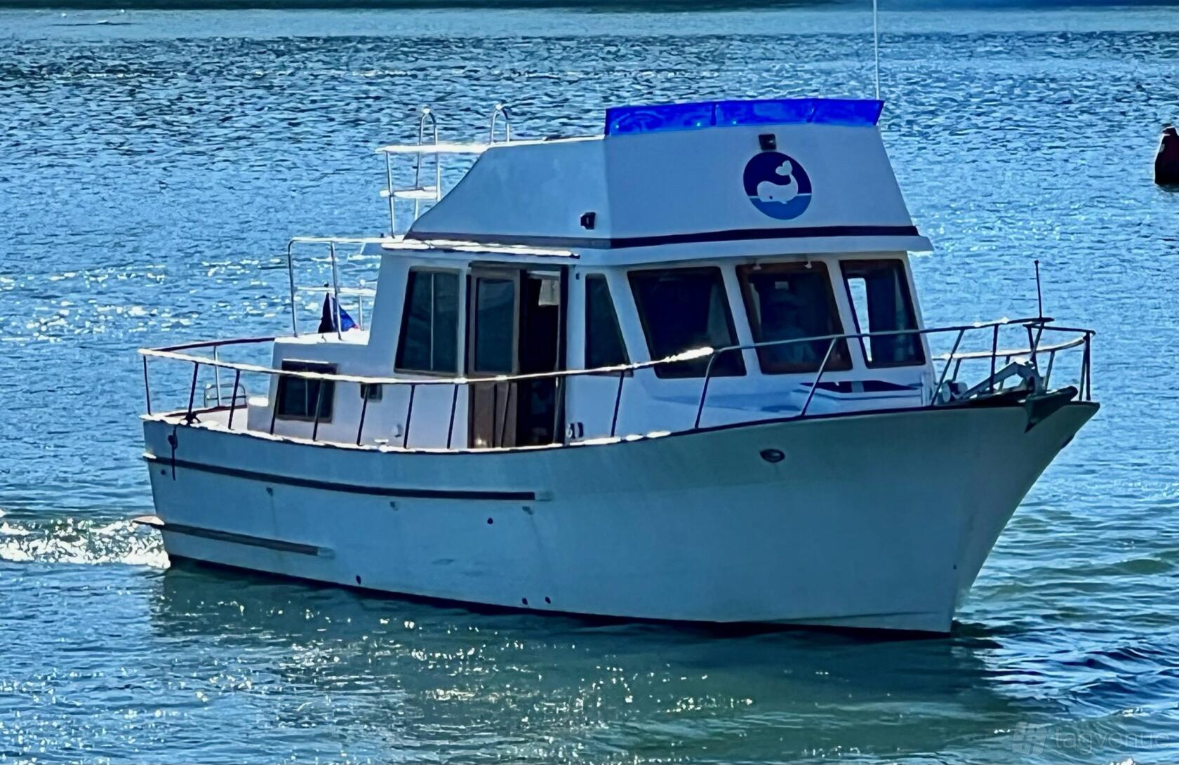 A white yacht with an enclosed cabin and upper deck on the water at Blue Skies Yacht.