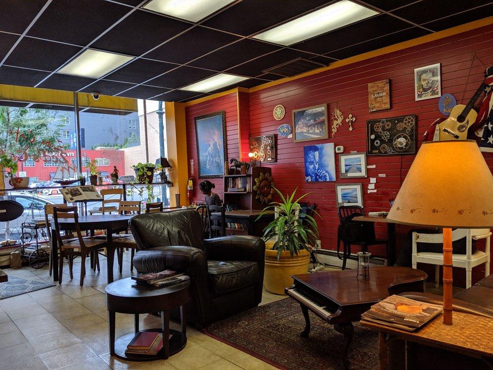 A cafe with leather armchairs, eclectic wall art, and large windows facing the street at Zed's Cafe.