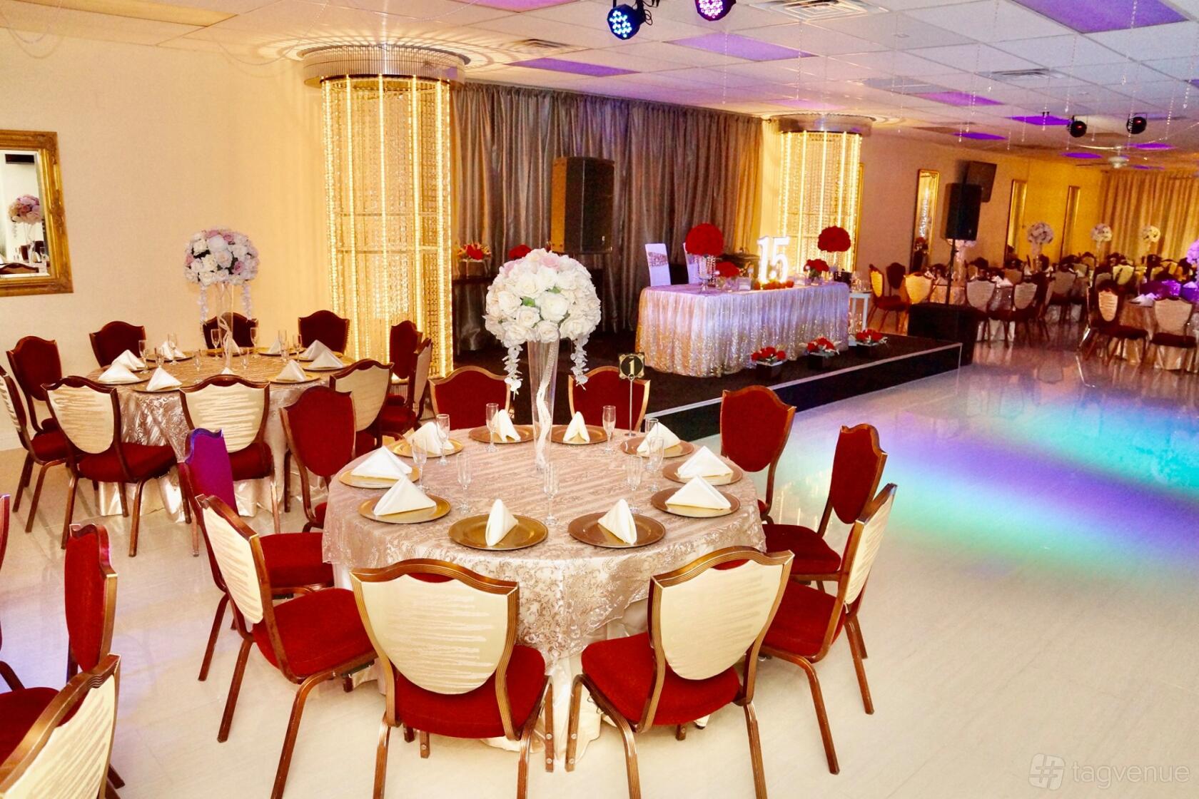 A banqueting hall with round tables draped in gold linens, red chairs, and floral centerpieces at Crystal Hall Banquets.