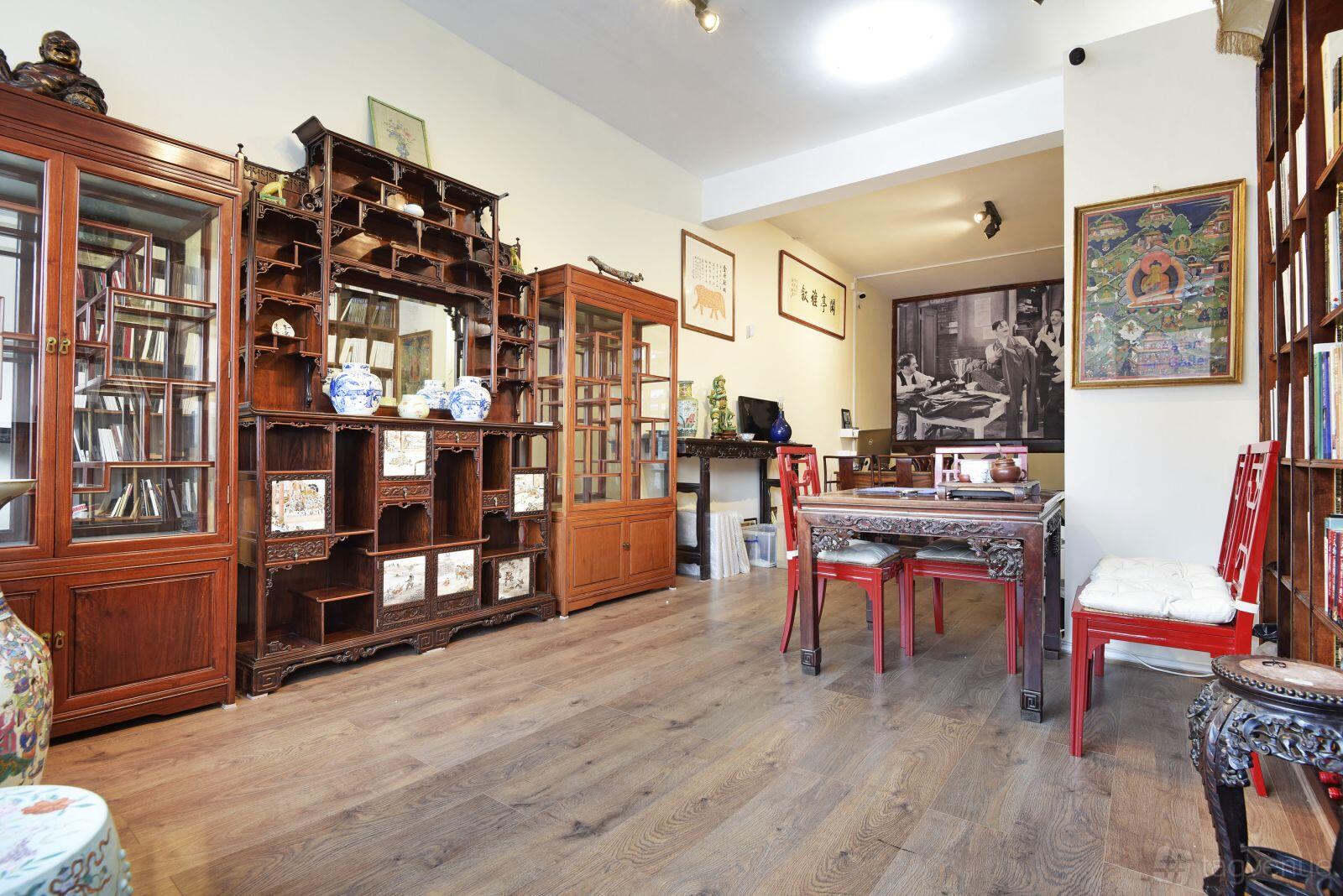 An art studio with wooden display shelves, traditional Chinese decor, and red chairs at Kang & Son.