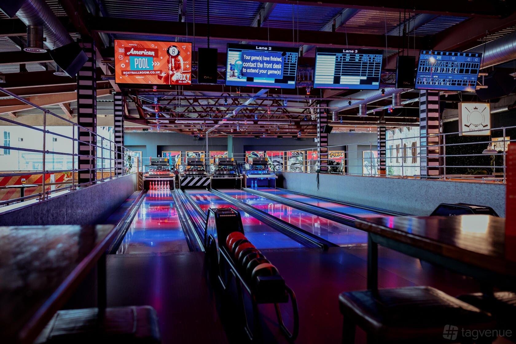 An event space in a bar with neon-lit bowling lanes, overhead screens, and arcade machines at Roxy Ball Room Liverpool Cavern Quarter.