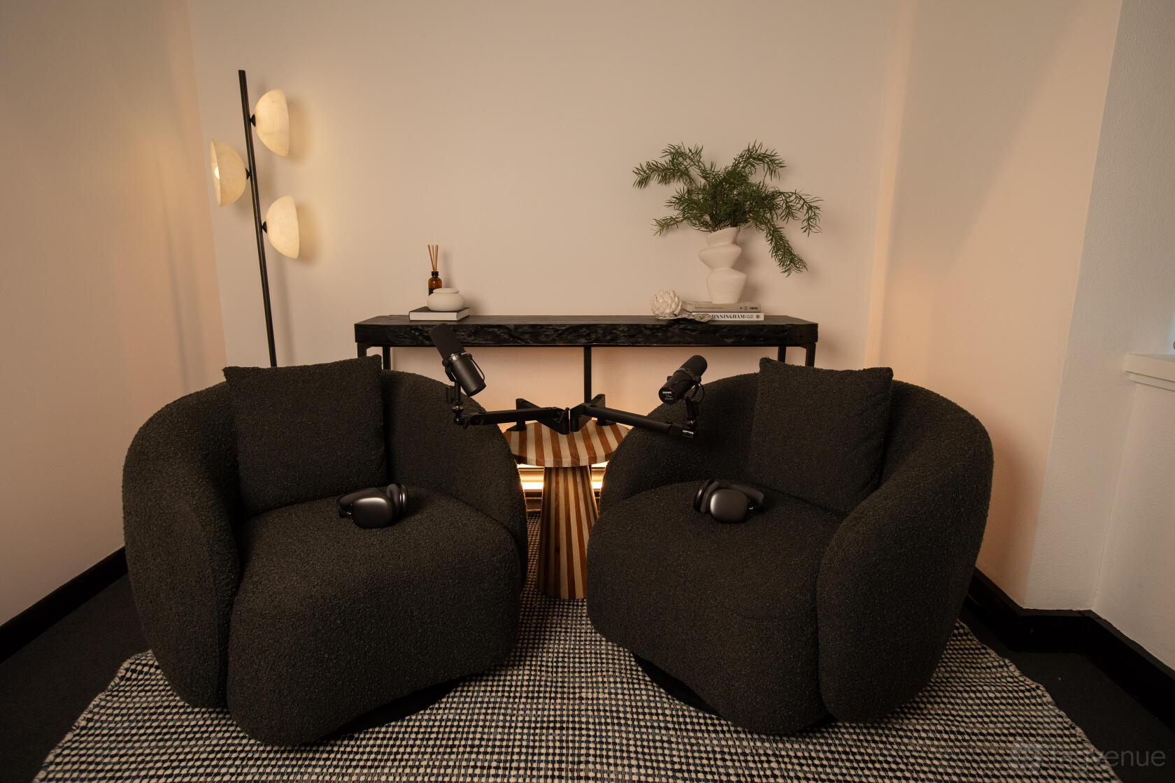 A podcast studio with two black armchairs, microphones on stands, and a decorative side table at Pro Podcast Studio.
