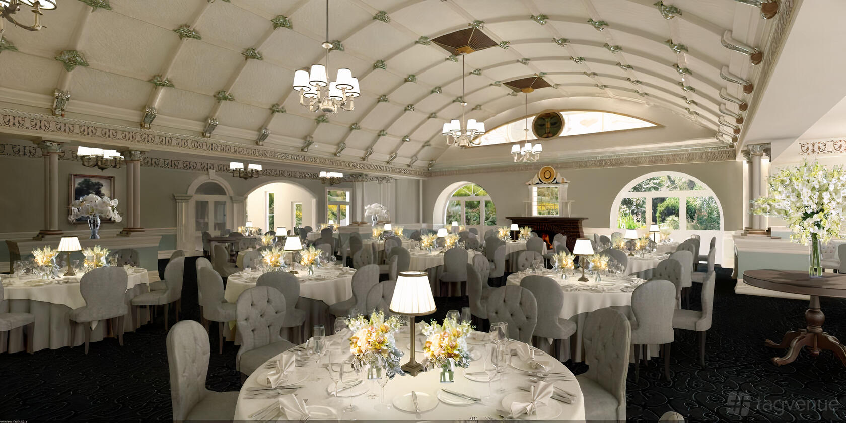 A hotel ballroom with round tables with white linens, tufted chairs, chandeliers, and arched windows at Hydro Majestic Blue Mountains.