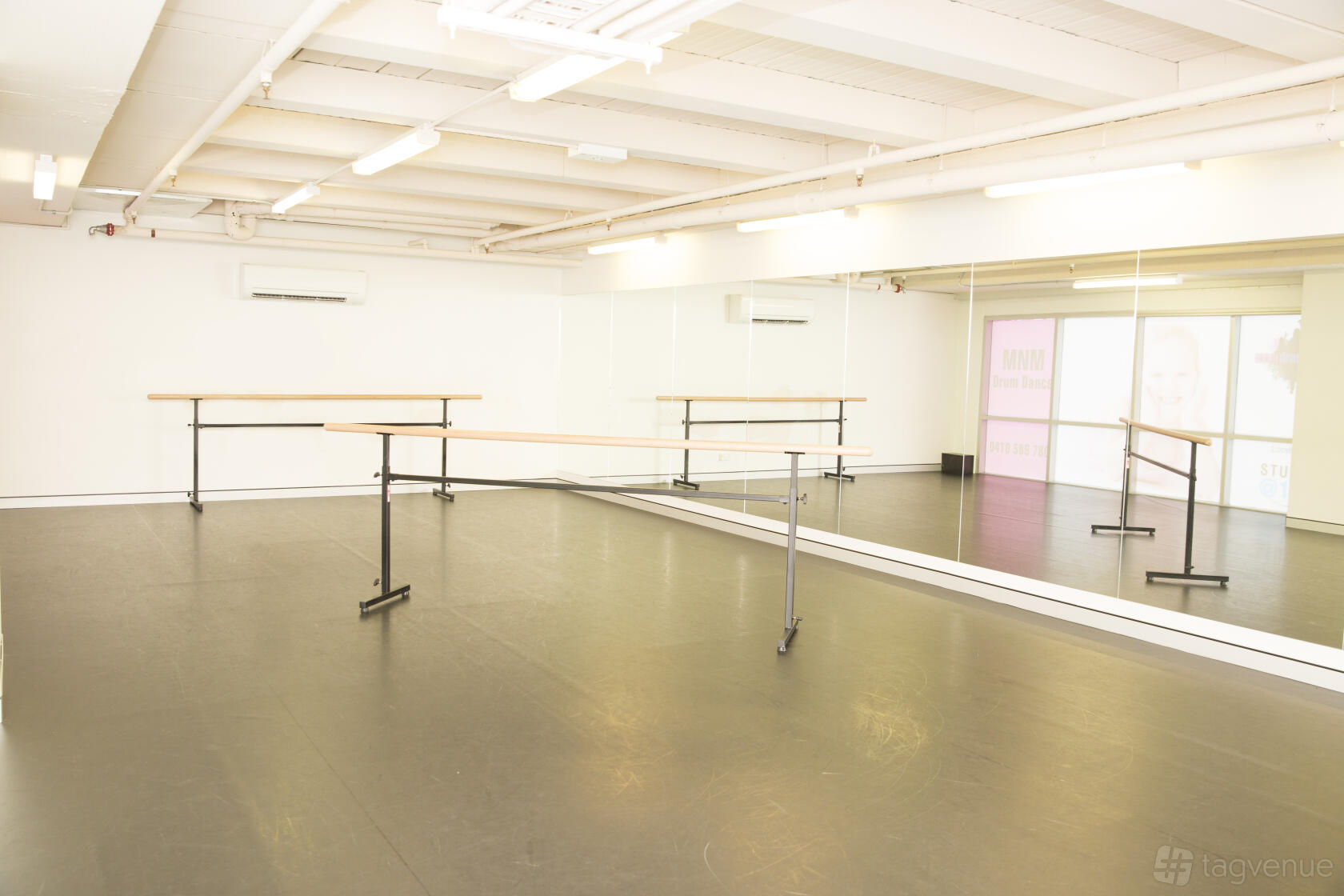 A dance studio with mirrored walls, ballet barres, and a black sprung floor at Studio at 104.