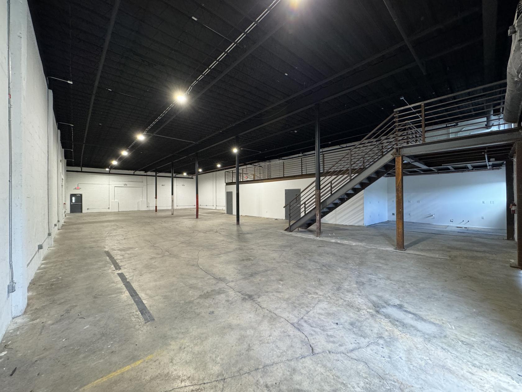 An event venue with polished concrete floors, open layout, and a metal staircase at Ironsbend.