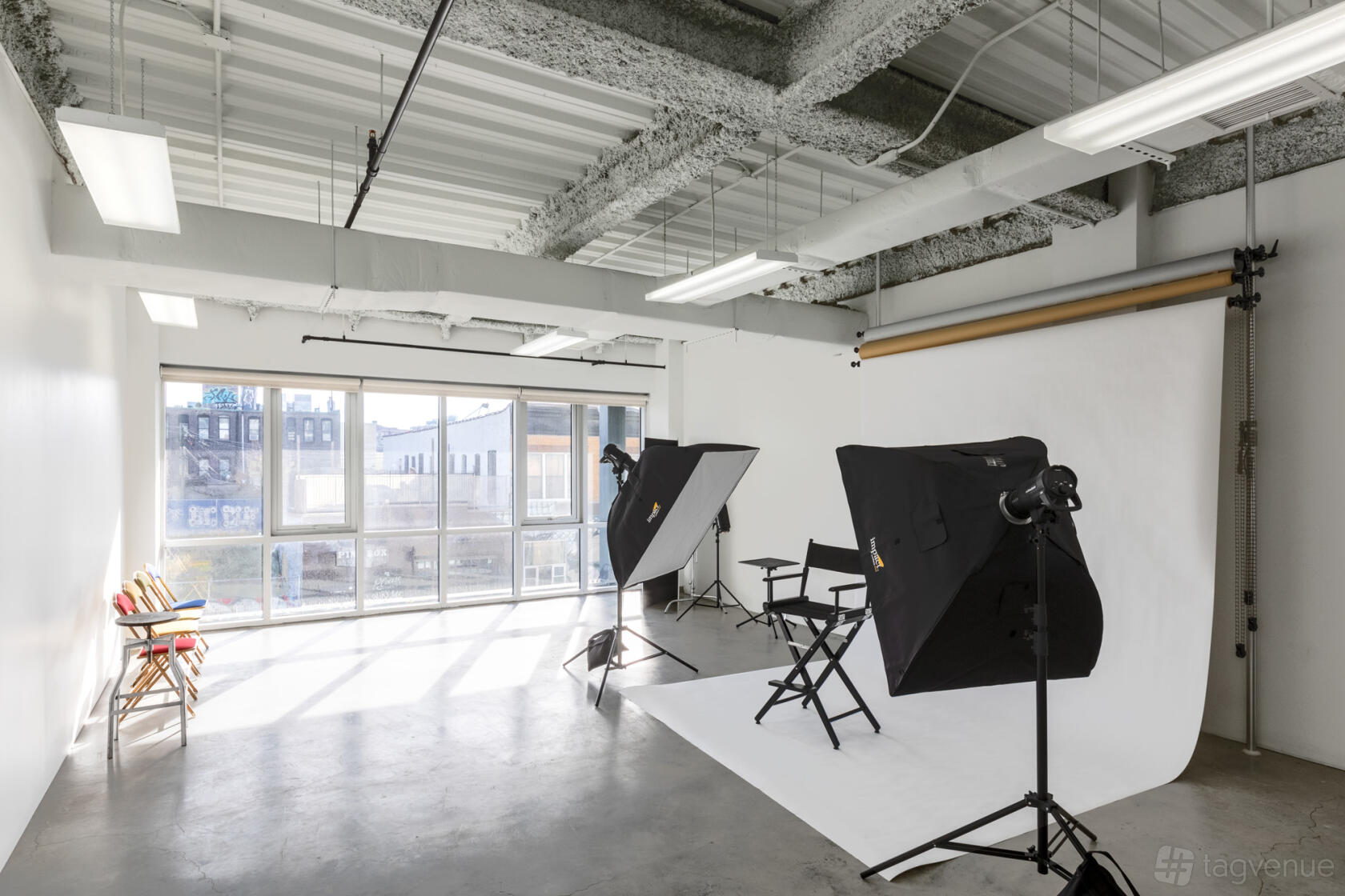 A photo studio with large windows, white backdrop, and professional lighting equipment at Grattan Studio.