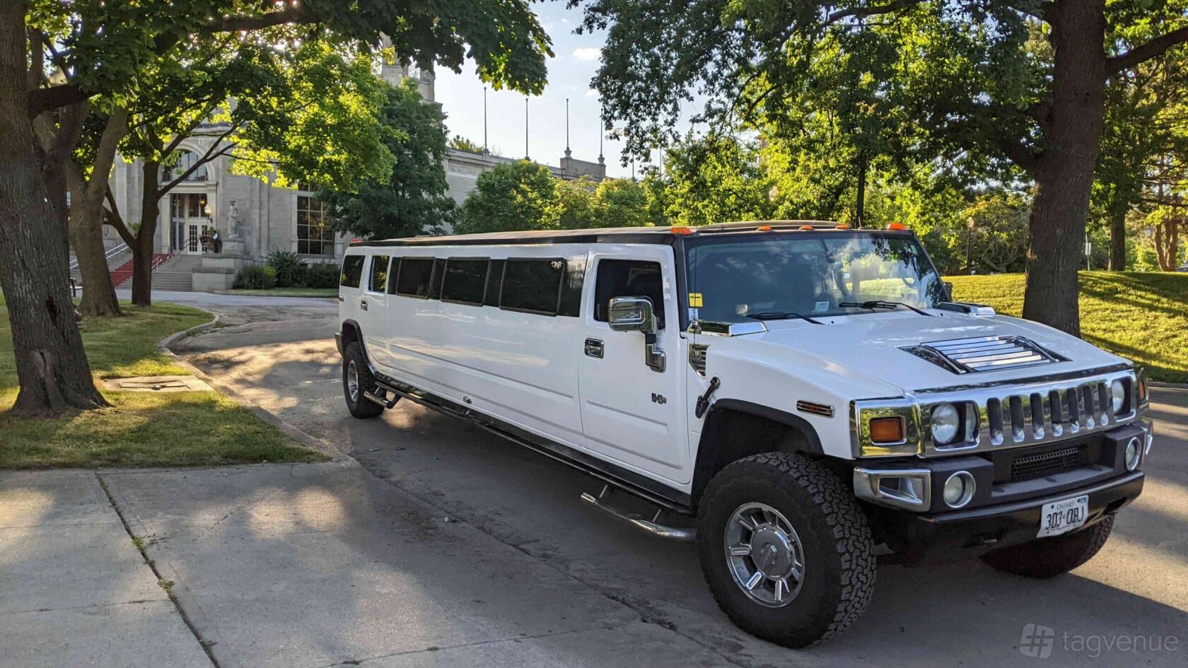 A white stretch Hummer H2 limousine with tinted windows parked under trees at GoodTime Limo & Party Buses - Mississauga.