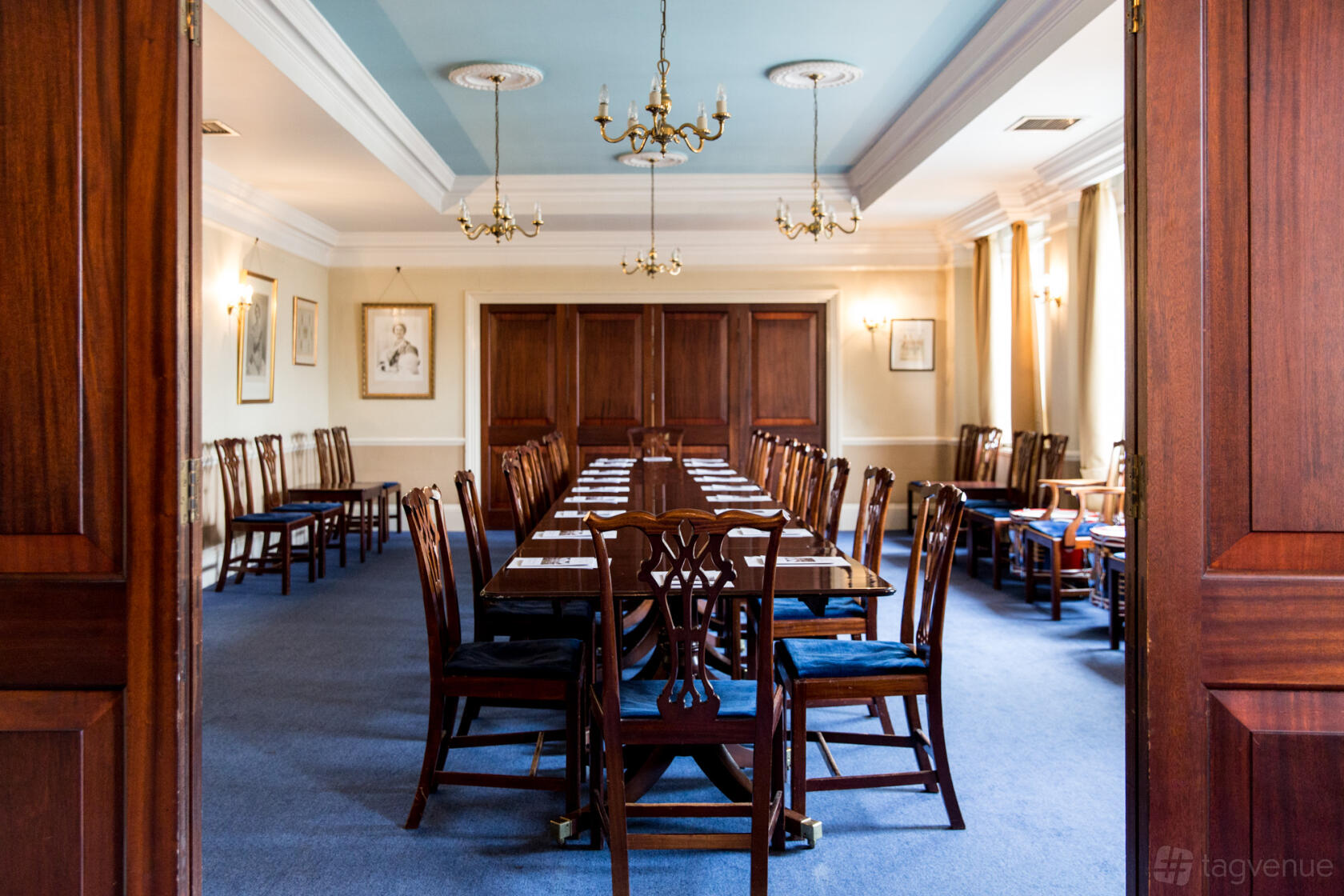 An event venue with long wooden tables, classic chairs, and chandeliers in the River Forth Room at London Scottish House.