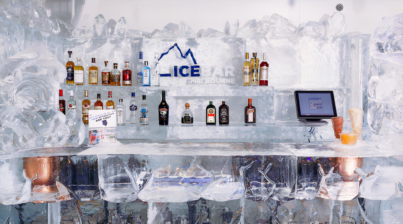 A bar with shelves and a counter made entirely of ice, stocked with liquor bottles at IceBar Melbourne.