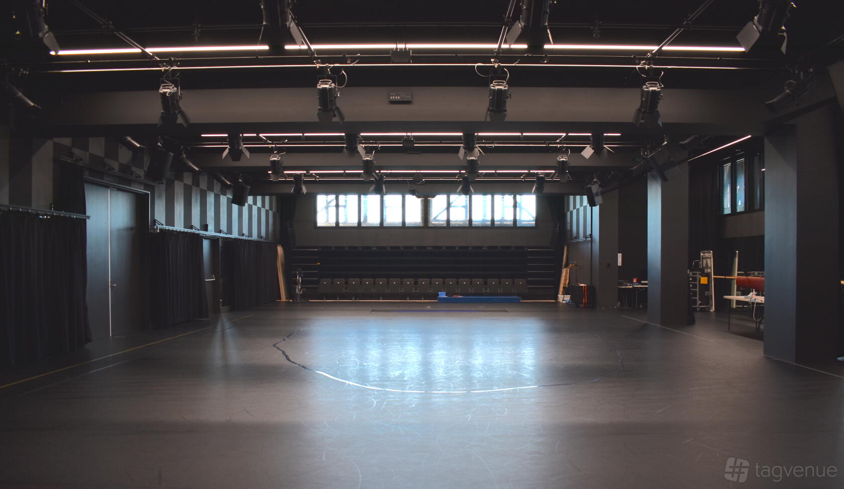A spacious dance studio with black marley flooring, high ceilings, exposed lighting, and large windows at Bangarra Dance Theatre.