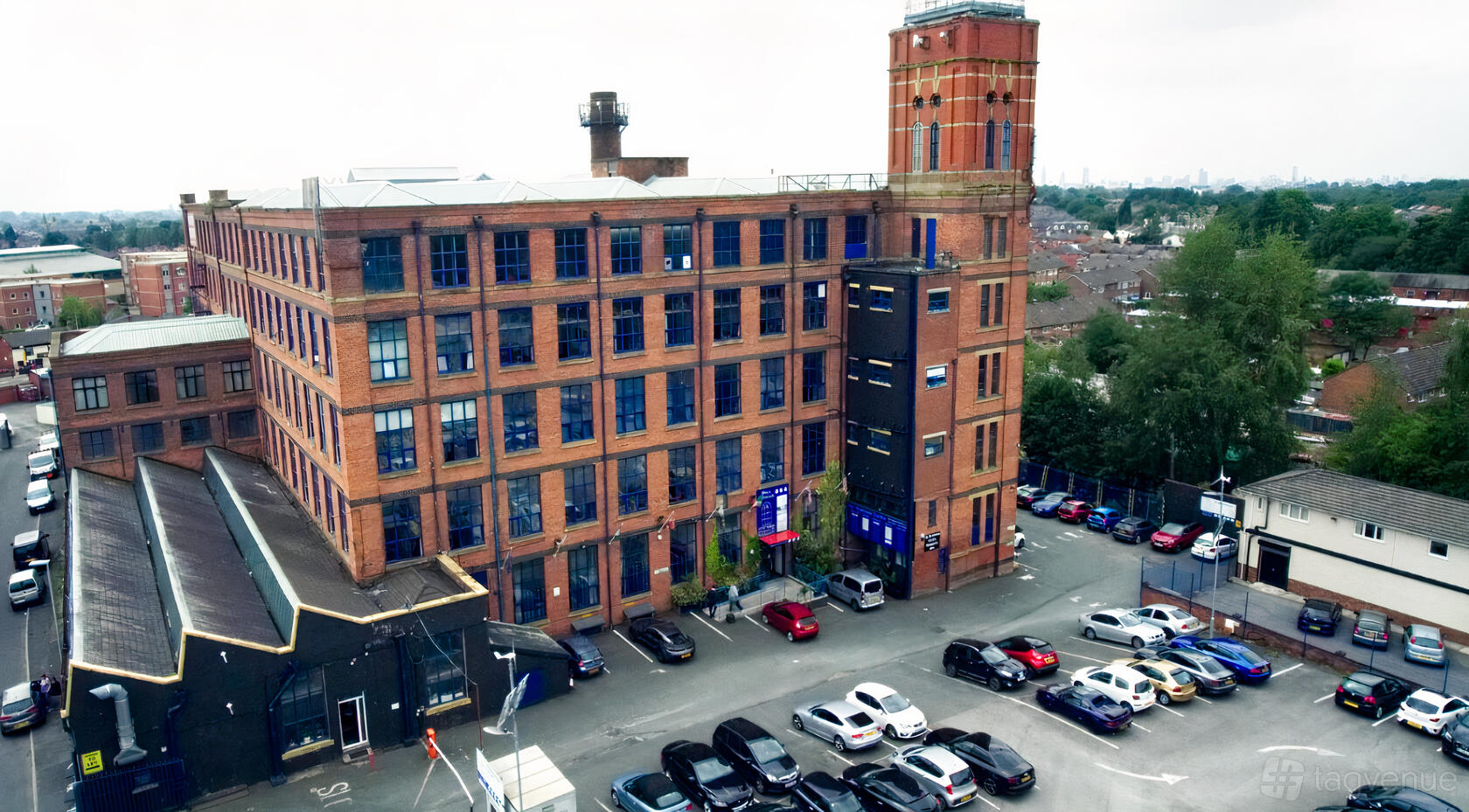 A brick industrial building with large grid windows and a parking lot at R360 Studio.