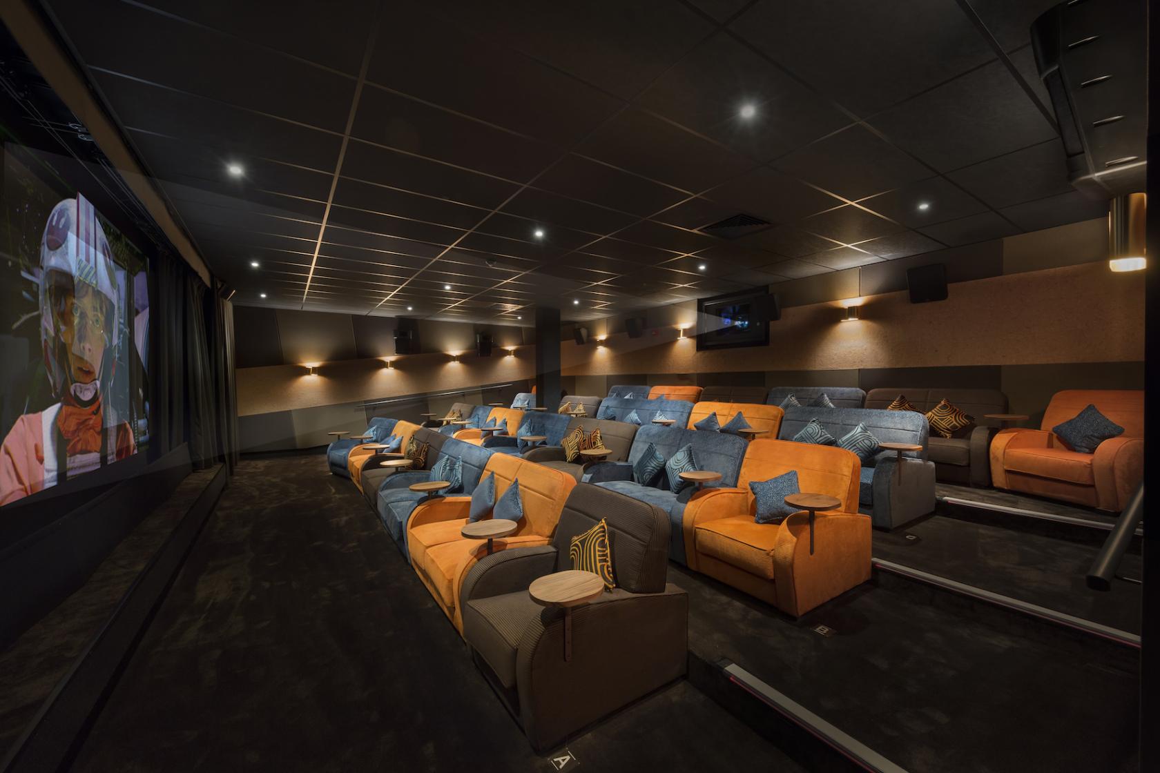 An auditorium-style cinema with plush sofas, side tables, and a large projection screen at Everyman Harrogate.