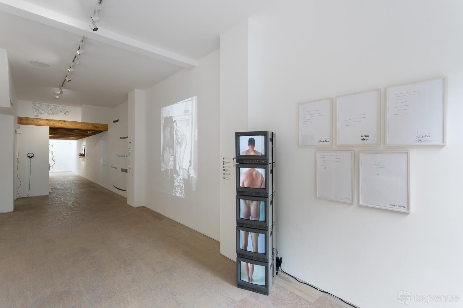 A contemporary gallery with white walls, wood flooring, and video art installations at Mimosa House.