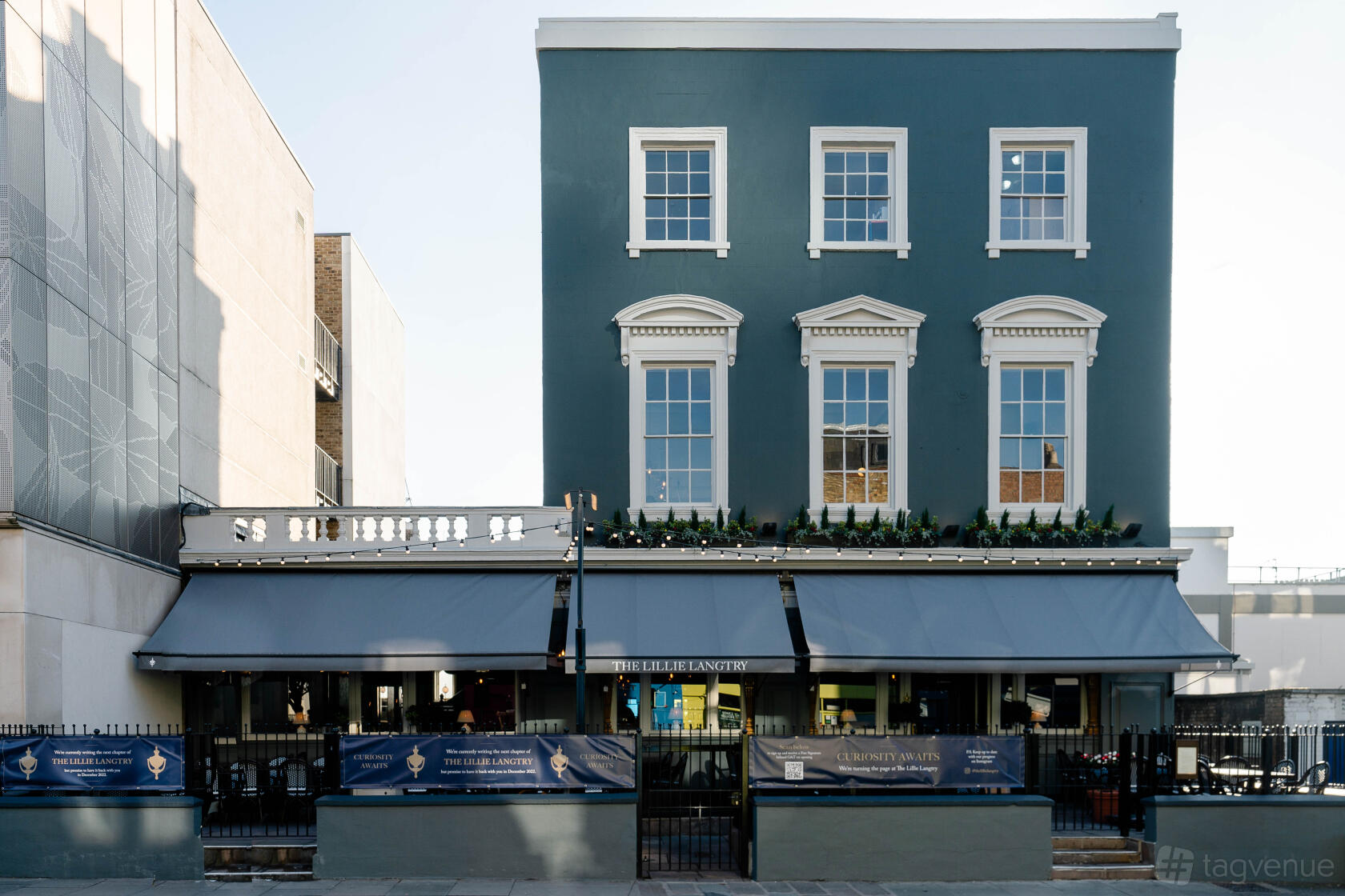 A traditional pub with a blue facade, white-trimmed windows, and outdoor awnings at The Lillie Langtry.