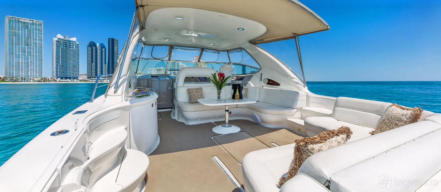 A boat with a covered open-air lounge, white leather seating, and ocean views at Beeyond Boats - Harbor West Marina Miami.
