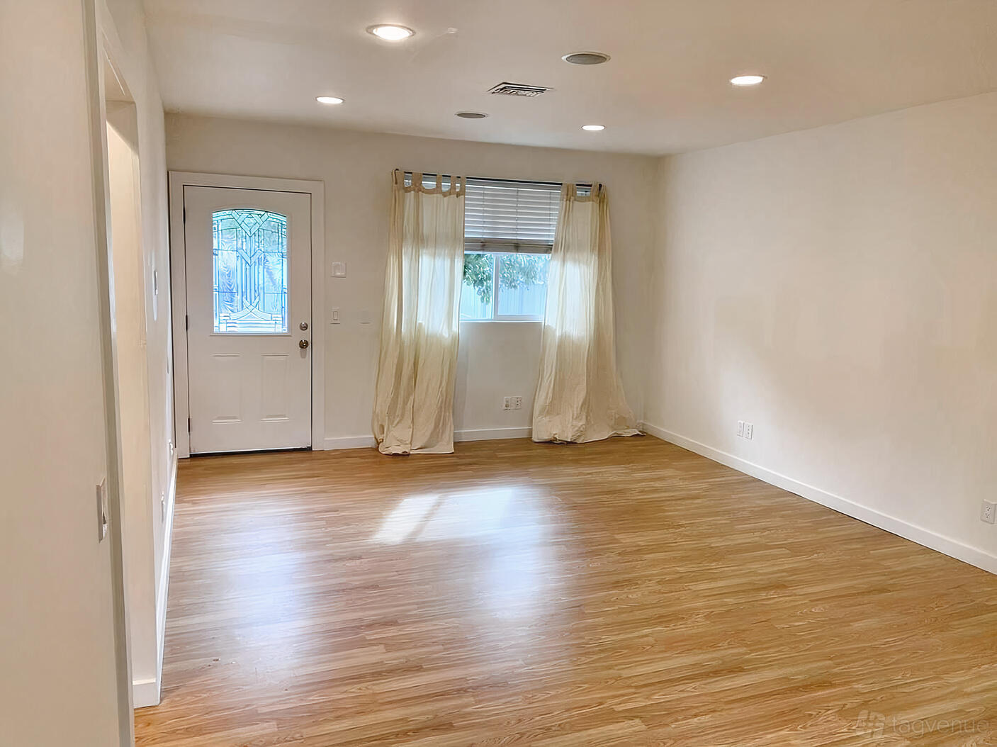 An event venue with light wood floors, recessed lighting, and a large window with sheer curtains at FWD Vision Spaces Thrive.