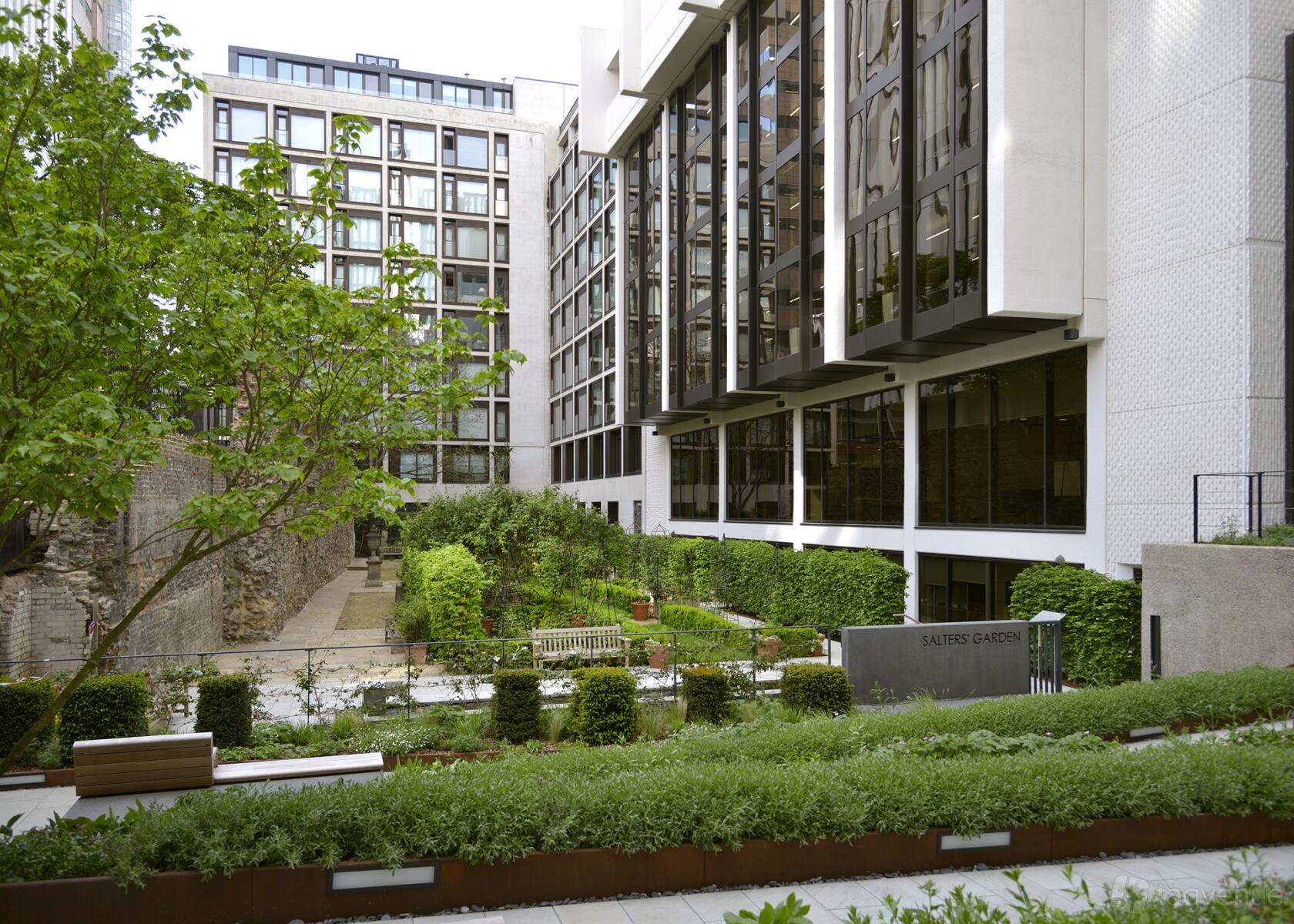 A hall with landscaped gardens, benches, and modern glass façades at Salters’ Hall.