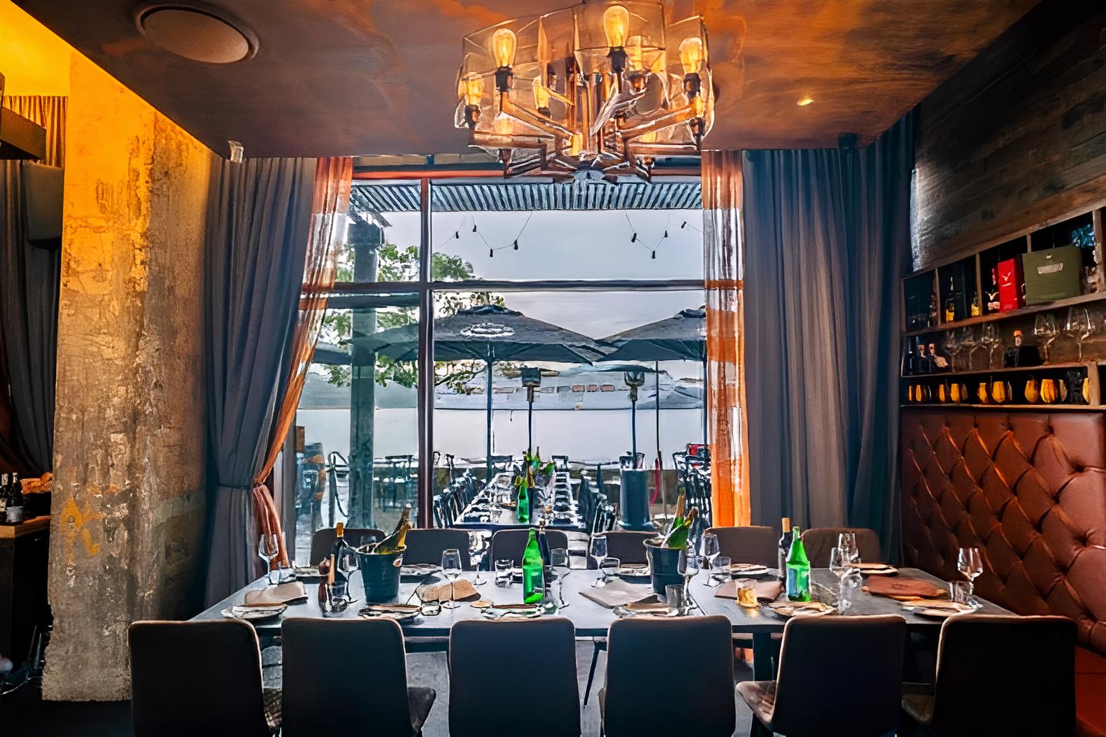 A restaurant private dining room with a chandelier, long table set for guests, and floor-to-ceiling windows at Elements Bar & Grill Pyrmont.