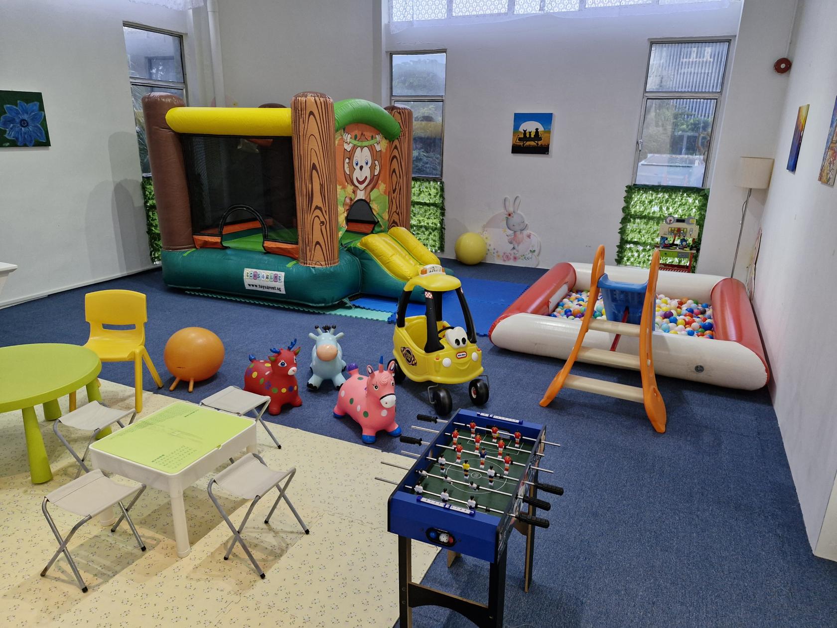 An event venue with a bouncy castle, ball pit, foosball table, and colorful kids’ play furniture at Toys4Rent.