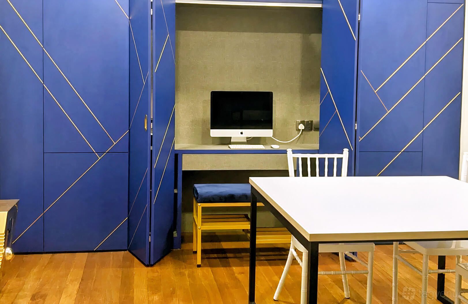 A function room with blue built-in cabinetry, a computer workstation, and a white table at The Common Good (TCG).