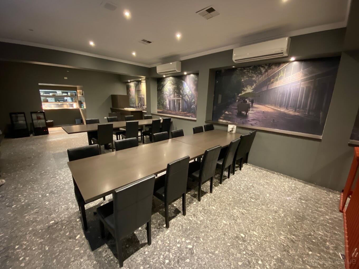 A restaurant with long dark tables, black chairs, gray terrazzo flooring, and large wall art at Sunshine Motor Inn.