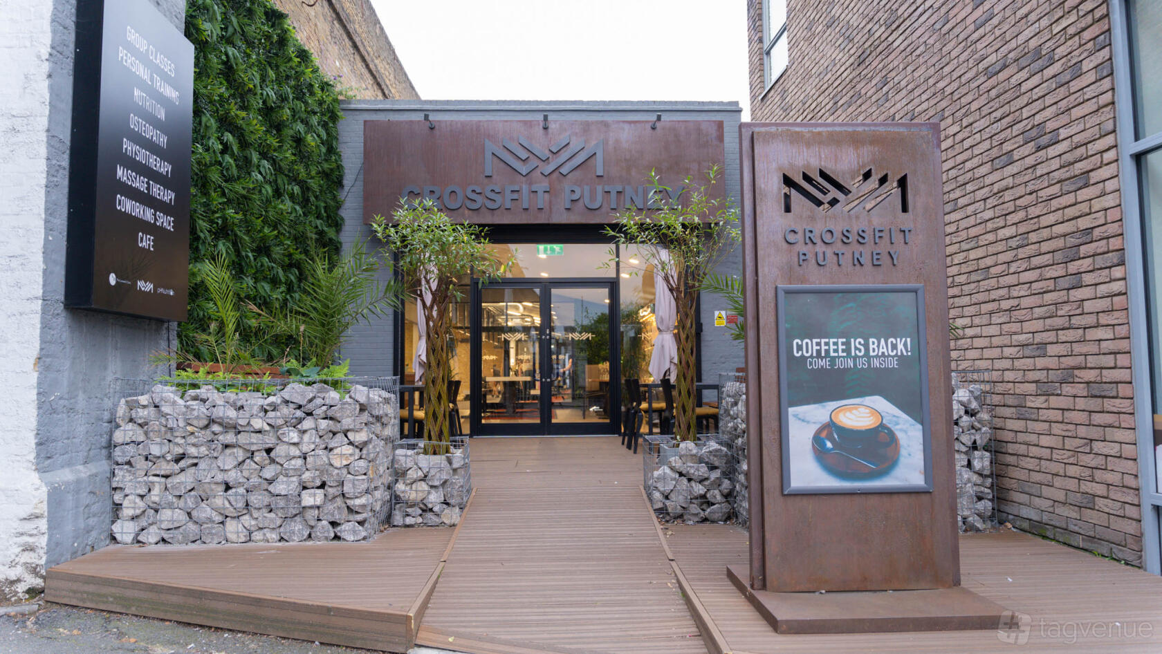 A railway arch venue with a stone entryway, greenery, and outdoor signage at CrossFit Putney.
