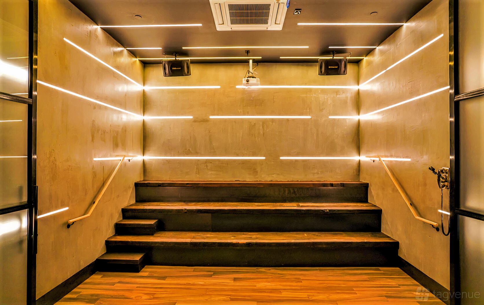 A VIP room with tiered wooden seating and horizontal LED wall lights at MS. KIM'S Lounge & Private Karaoke.