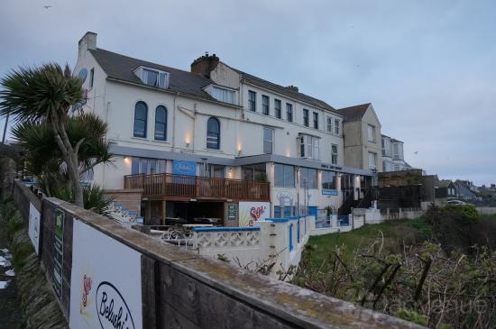A coastal pub with outdoor seating areas and a large deck overlooking greenery at Belushi's Newquay.
