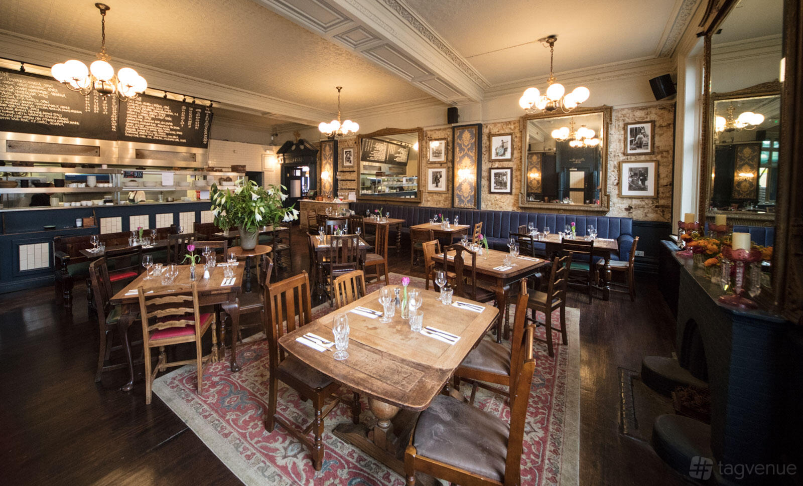 A dining room with mismatched wooden tables, vintage decor, and framed photos on the walls at The Wheatsheaf Tooting.
