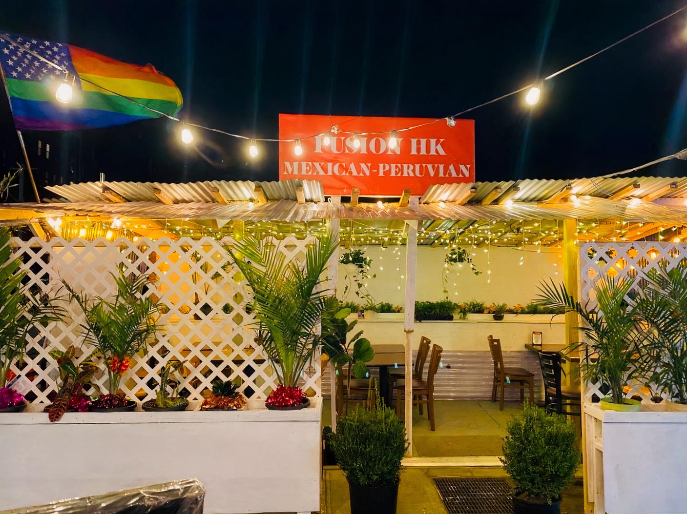 An outdoor restaurant event space with string lights, potted plants, and lattice dividers at Fusion HK Bar and Grill.