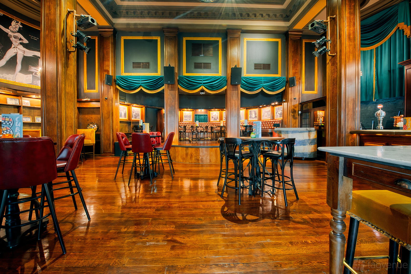 A function room with polished wood floors, teal drapes, and high ceilings at Revolucion De Cuba Birmingham.