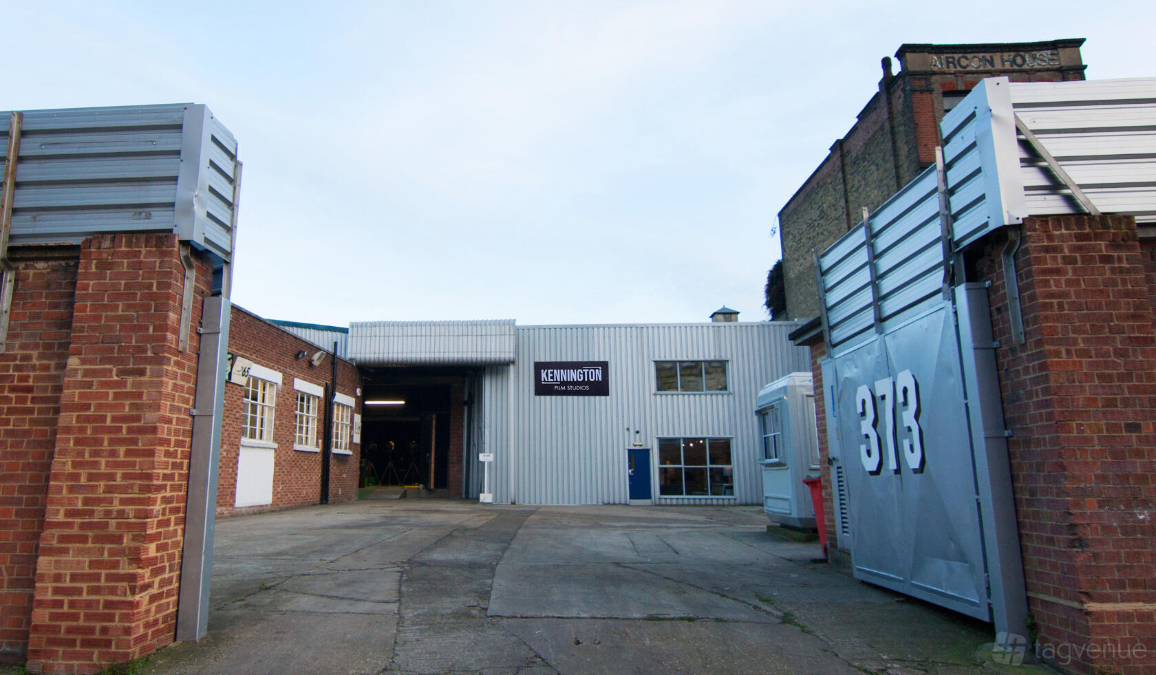 An industrial film studio with red brick walls, a wide gate, and metal exterior at Kennington Film Studios.