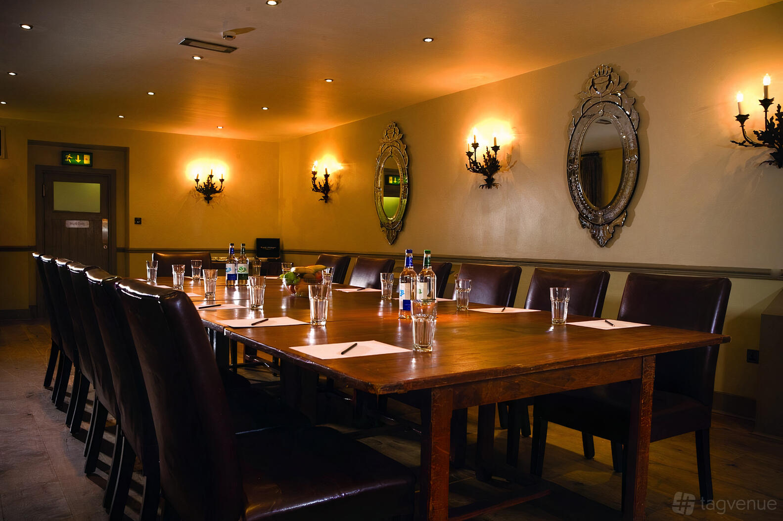 A hotel dining room with a long wooden table, leather chairs, wall sconces, and ornate mirrors at Hotel du Vin Henley-on-Thames.