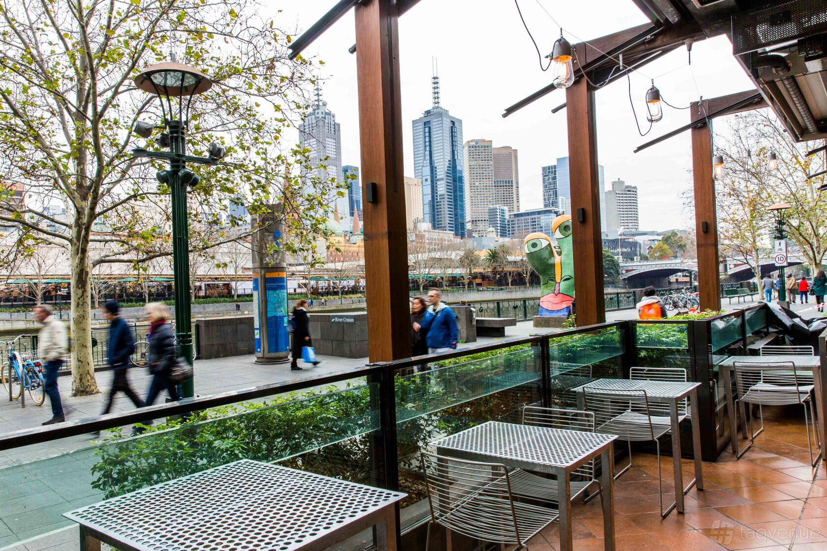A restaurant terrace with metal tables, glass railing, and city skyline views at BearBrass.