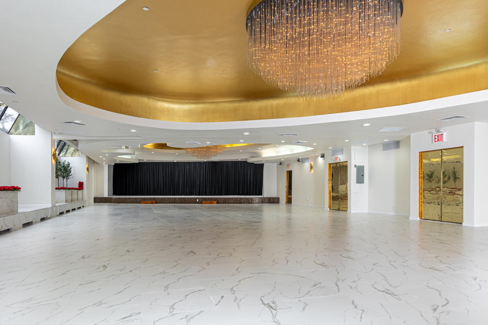 An event venue with marble floors, gold-accented ceilings, and a large crystal chandelier at Astoria World Manor.