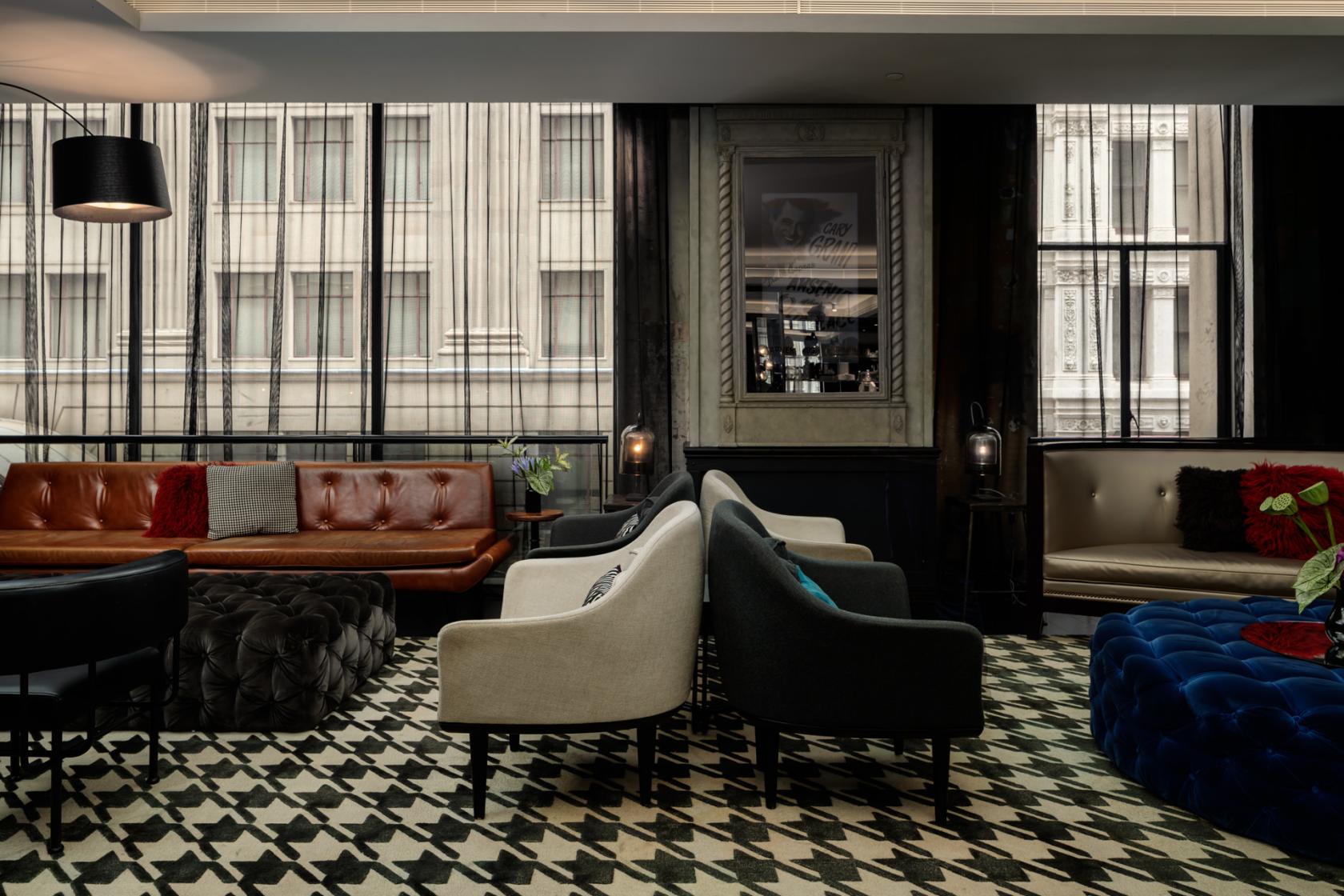 An event space with patterned flooring, eclectic lounge seating, and large windows at QT Sydney's Studio Q.