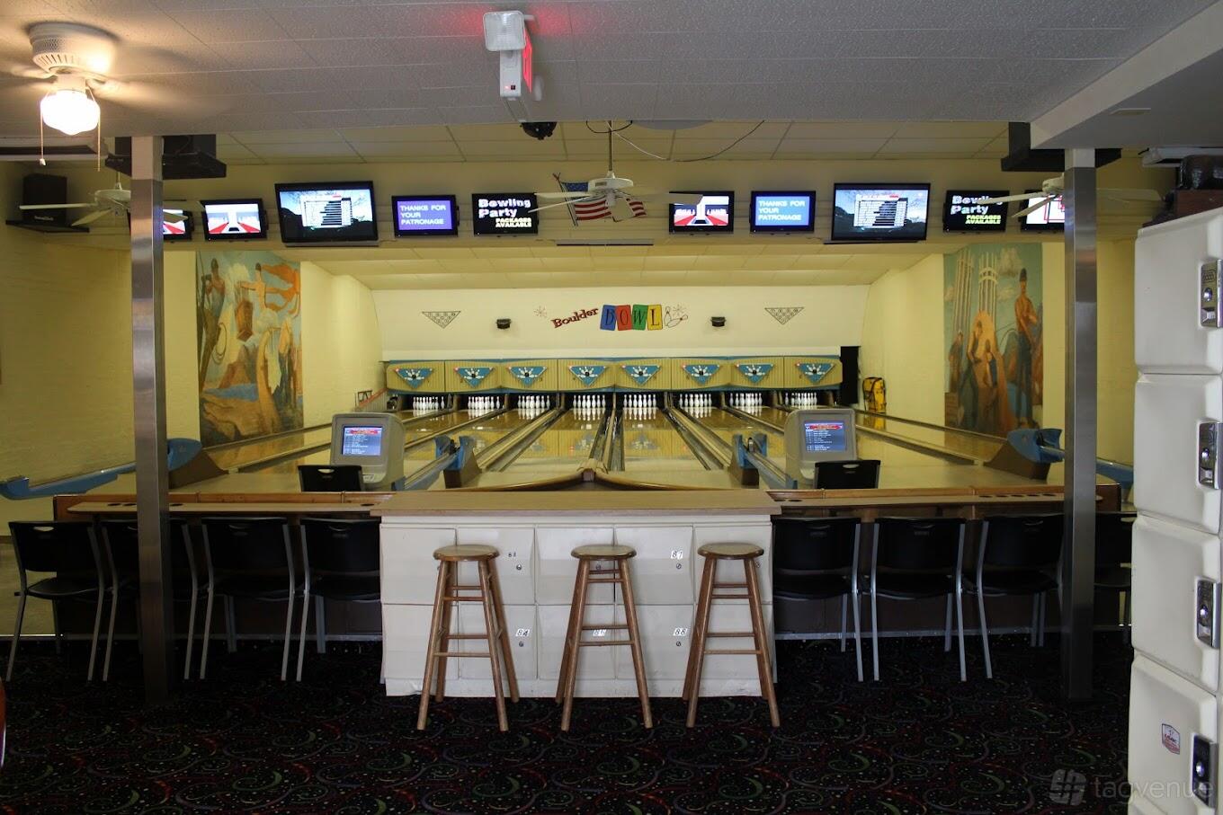 A bowling alley with mural-painted walls, multiple lanes, and high-top seating at Boulder Bowl.