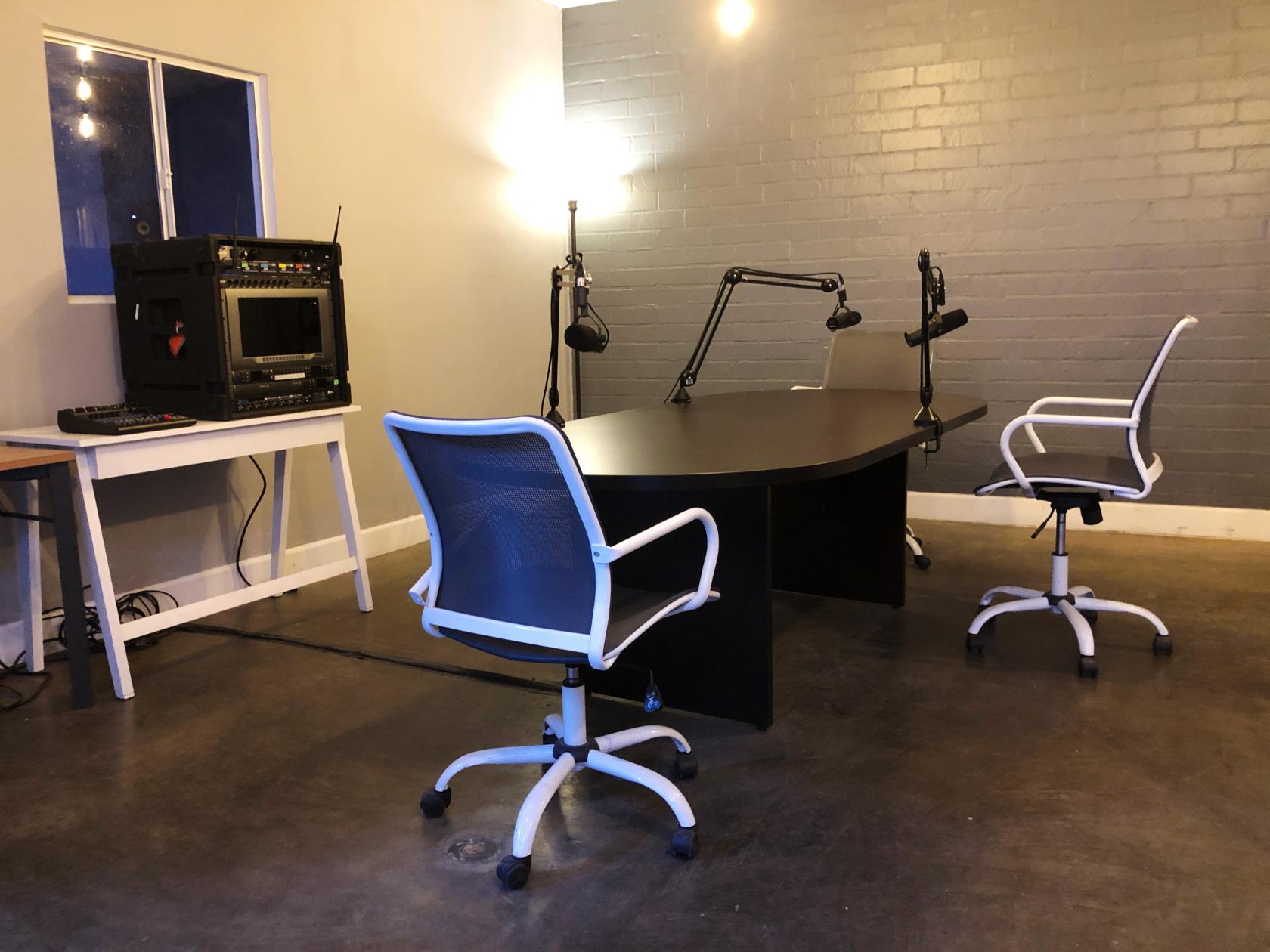 A podcast studio with adjustable microphones, sound equipment rack, and swivel chairs at Podcast Recording Studio Space.