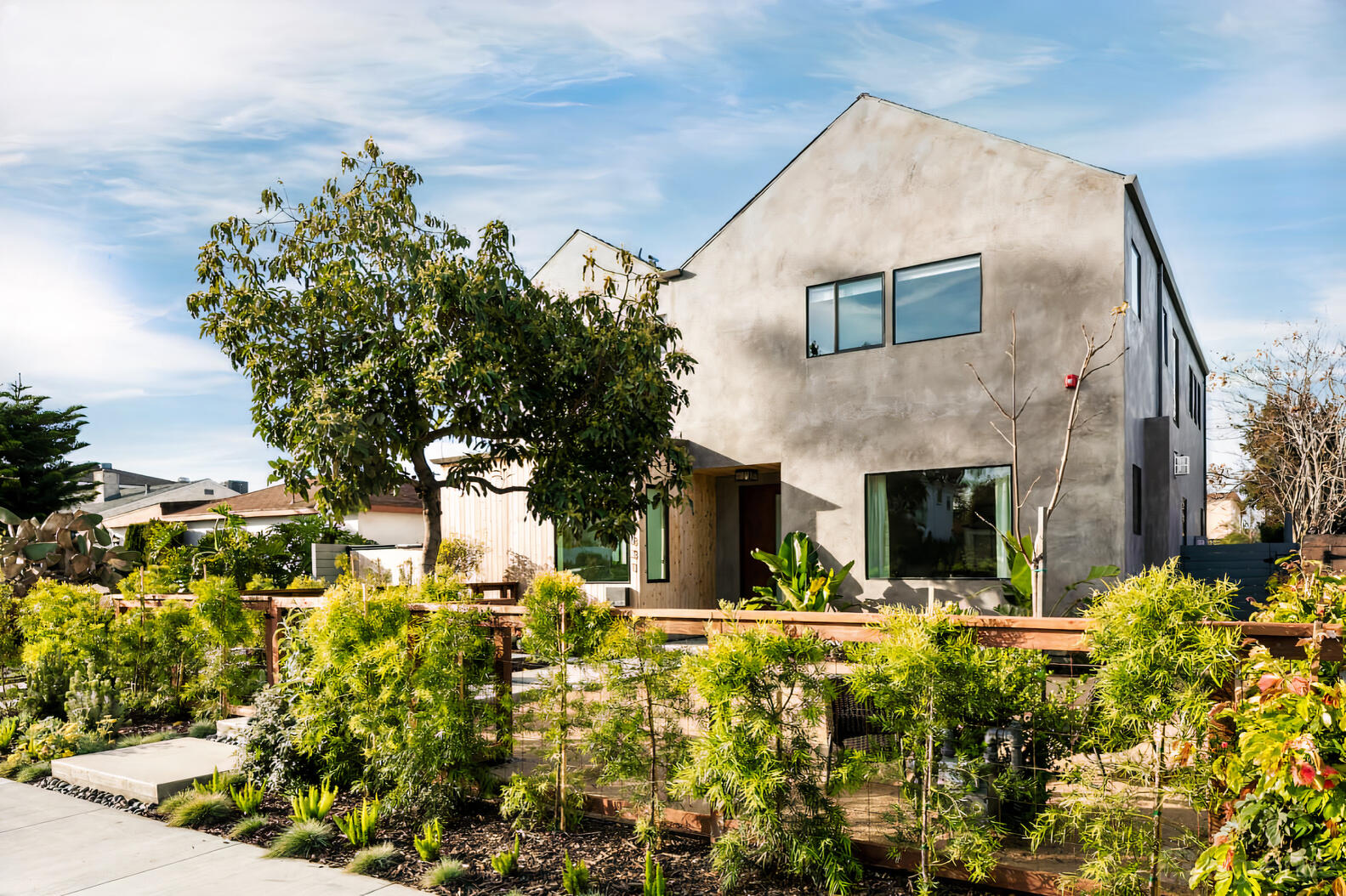 A modern apartment building with large windows, a landscaped garden, and natural wood fencing at Westside Architectural Home.