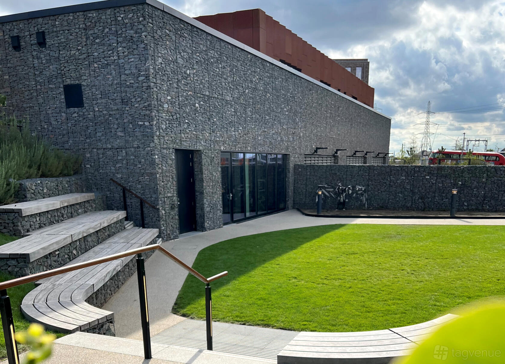 A versatile event space with stone walls, tiered wooden seating, and a lawn area at The Wilds.