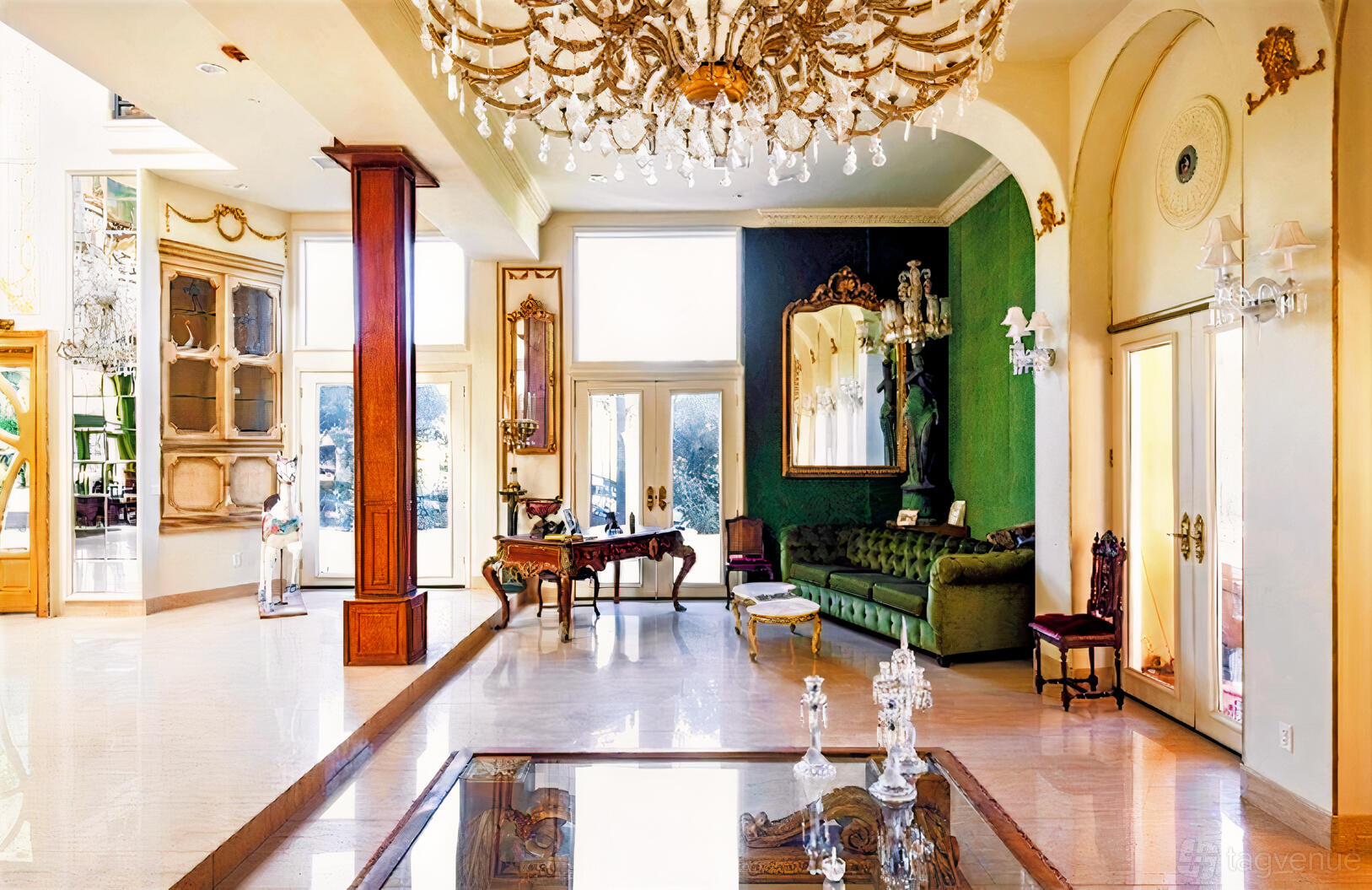 A house with a grand chandelier, green velvet sofa, ornate mirrors, and large windows at Sunset Estate.