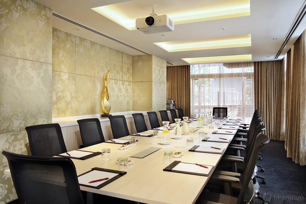 A boardroom with a long conference table, high-back chairs, and patterned walls at Village Hotel Katong.