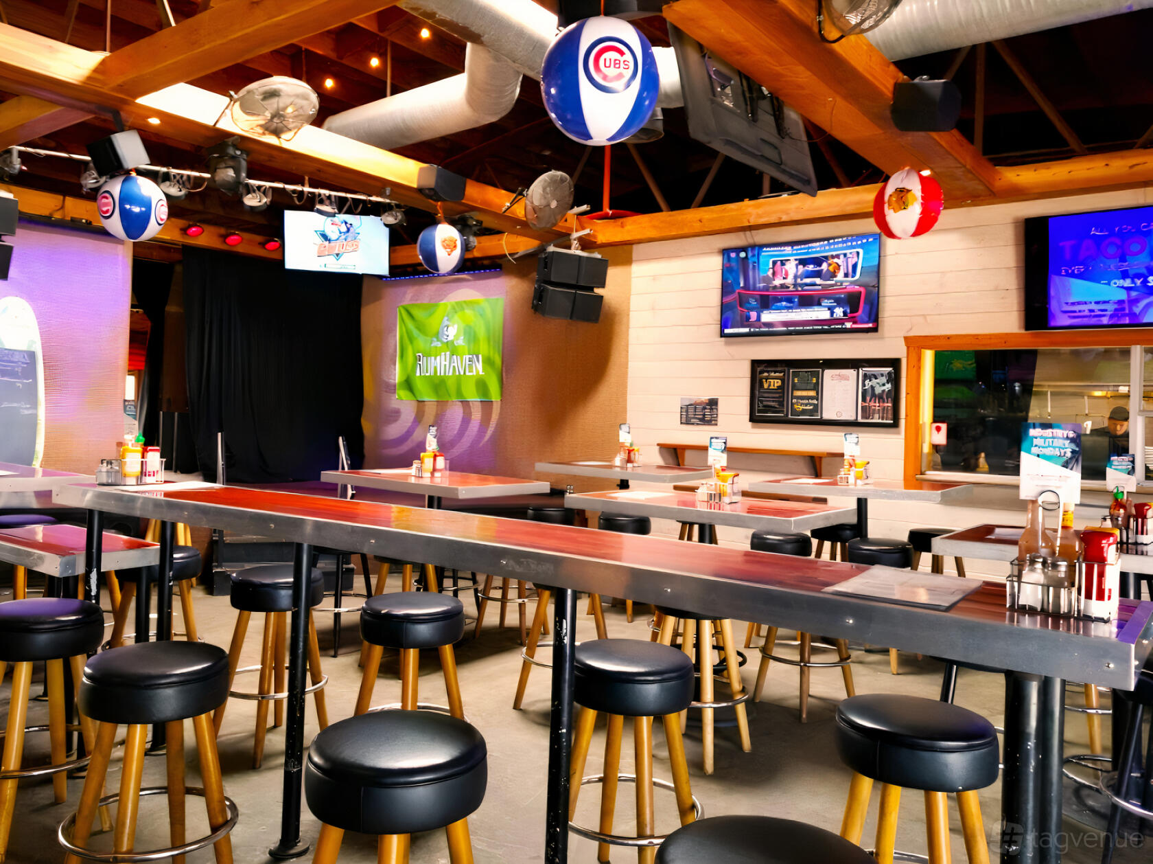 A restaurant with wooden beams, high-top tables, barstools, and a small stage at 710 Beach Club.